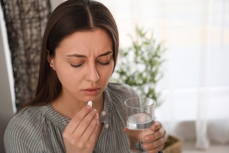 A Young Woman Visibly Upset While Holding a Glass of Water and an Abortion Pill Reversal